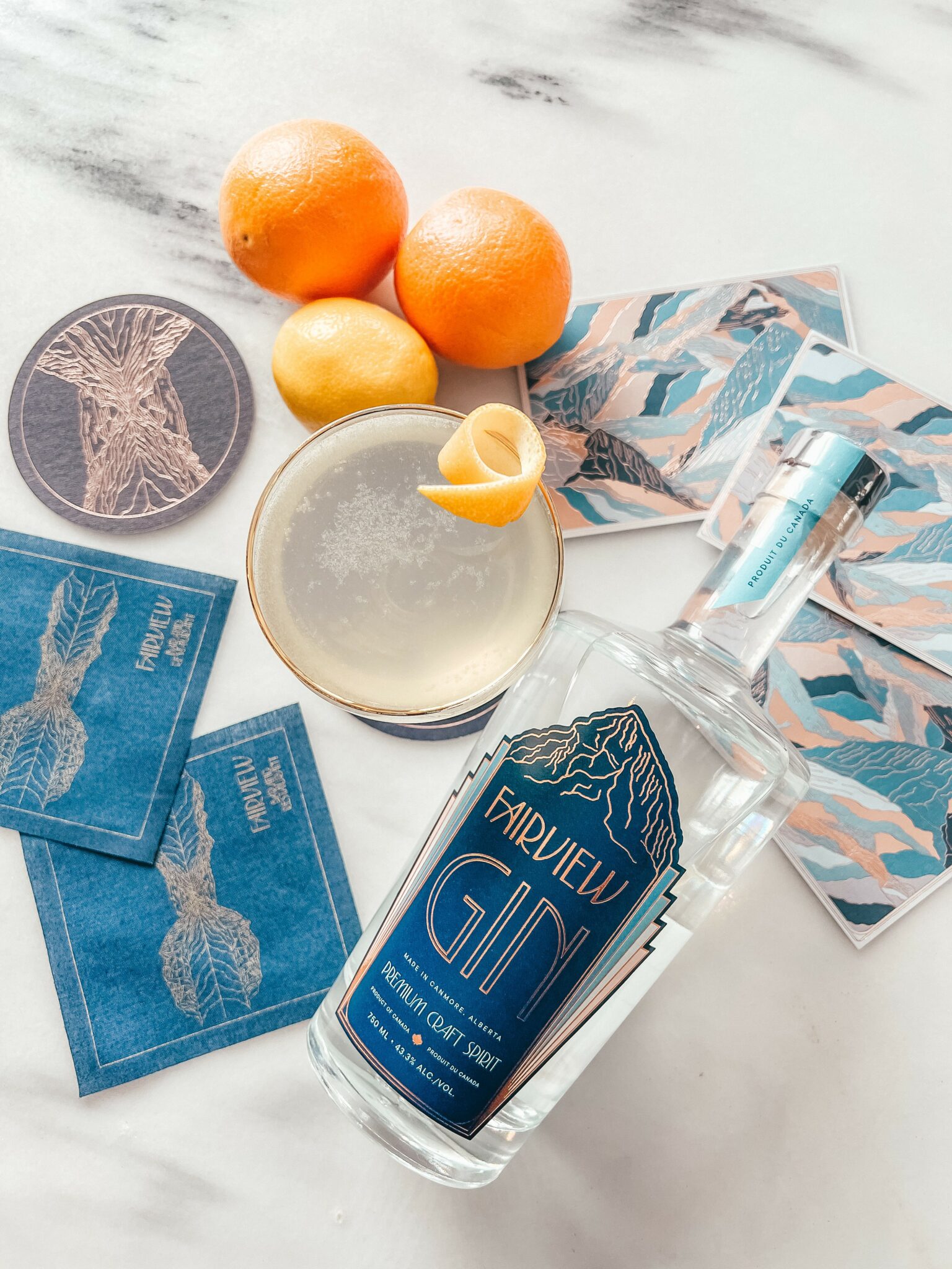 bottle of gin lays on a table beside a cocktail