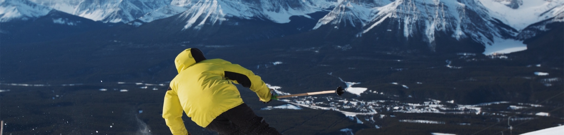 person in a yellow jacket skiing downhill