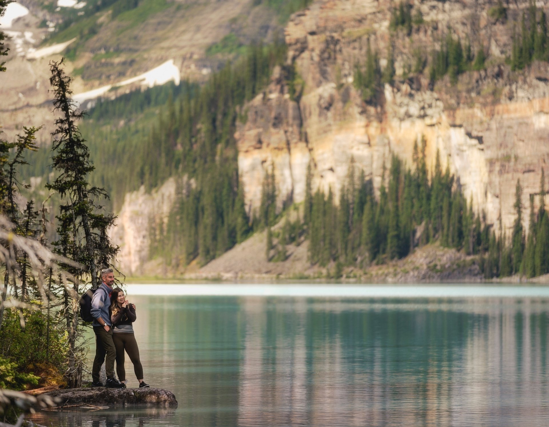 Two people embracing on the edge of Lake Louise