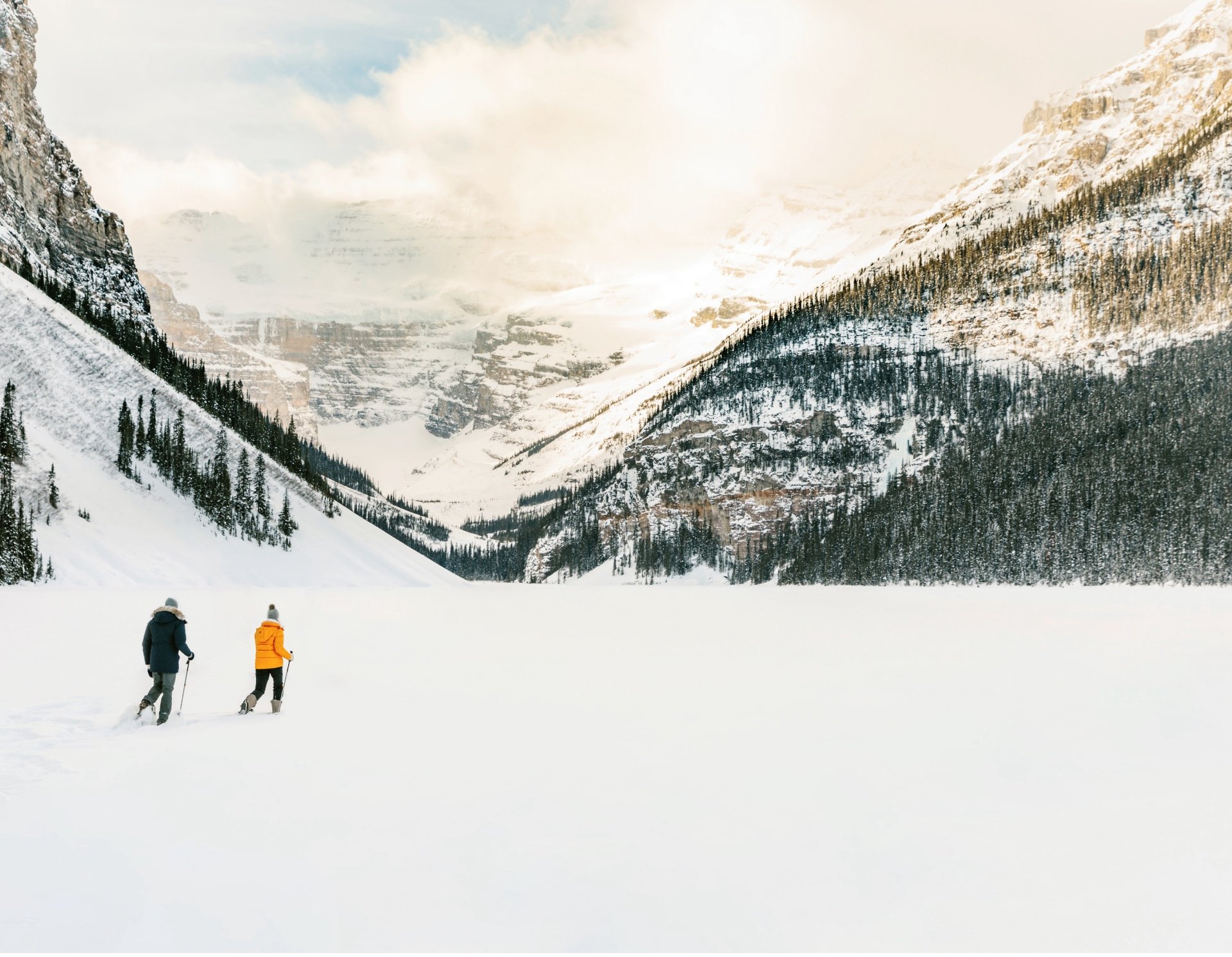 A man and a woman hiking through snow in the Lake Louise Banff mountains