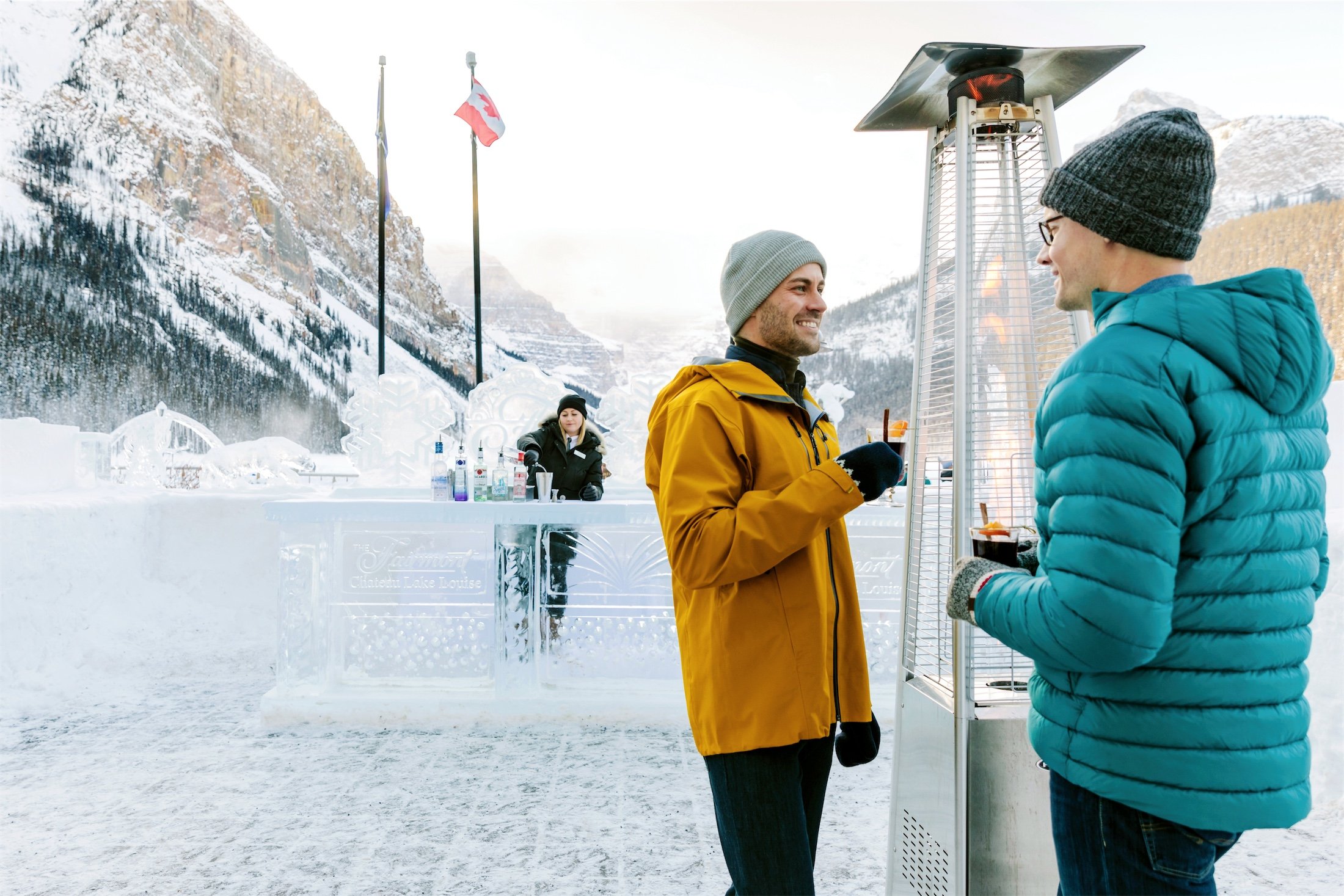 couple standing by the outdoor heater drinking hot drinks at the ice bar