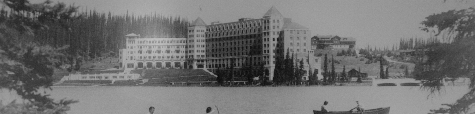 old black and white image of people canoeing on lake louise
