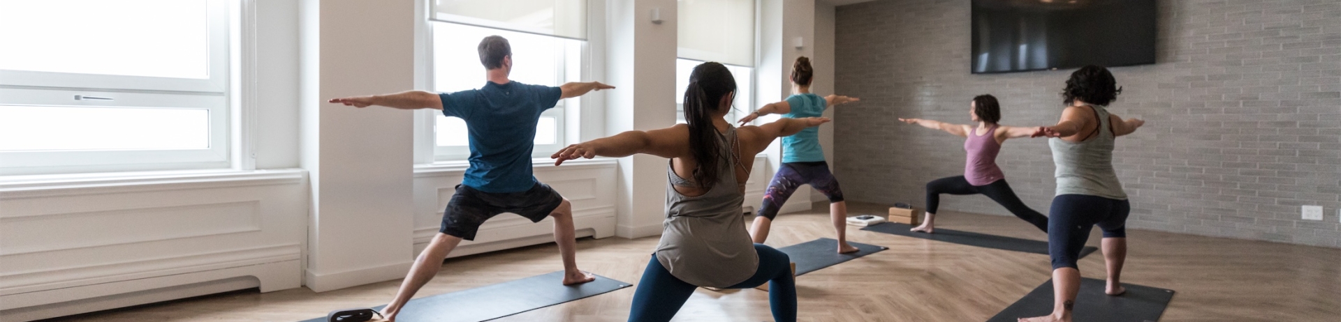 group of people in warrior two pose doing yoga in a studio