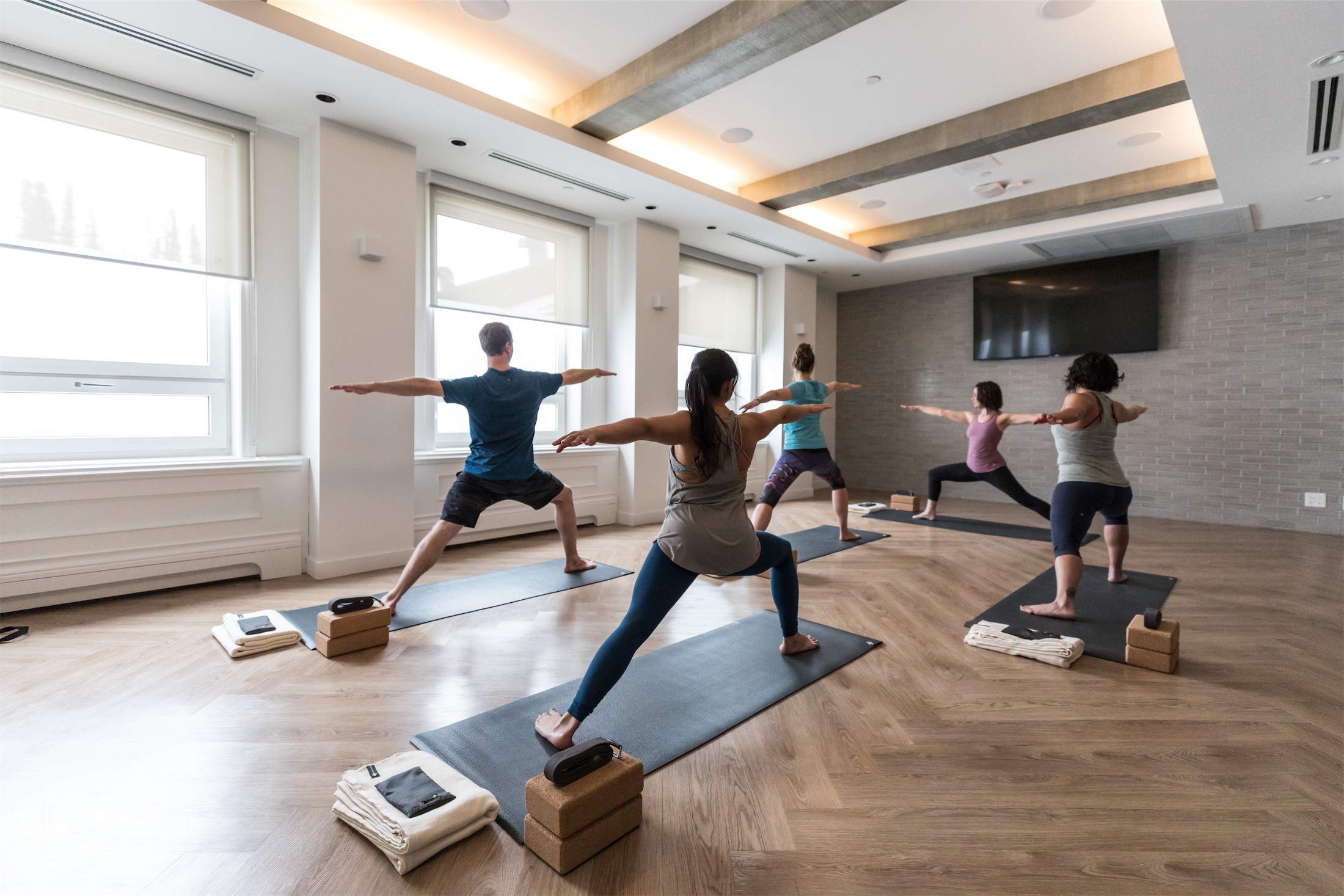 group of people in warrior two pose doing yoga in a studio