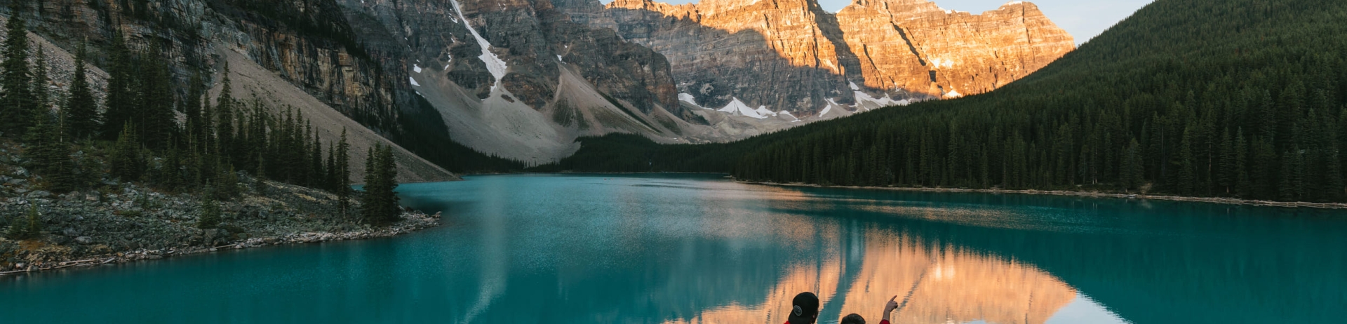 A couple standing by Lake Louise pointing at the surrounding mountains