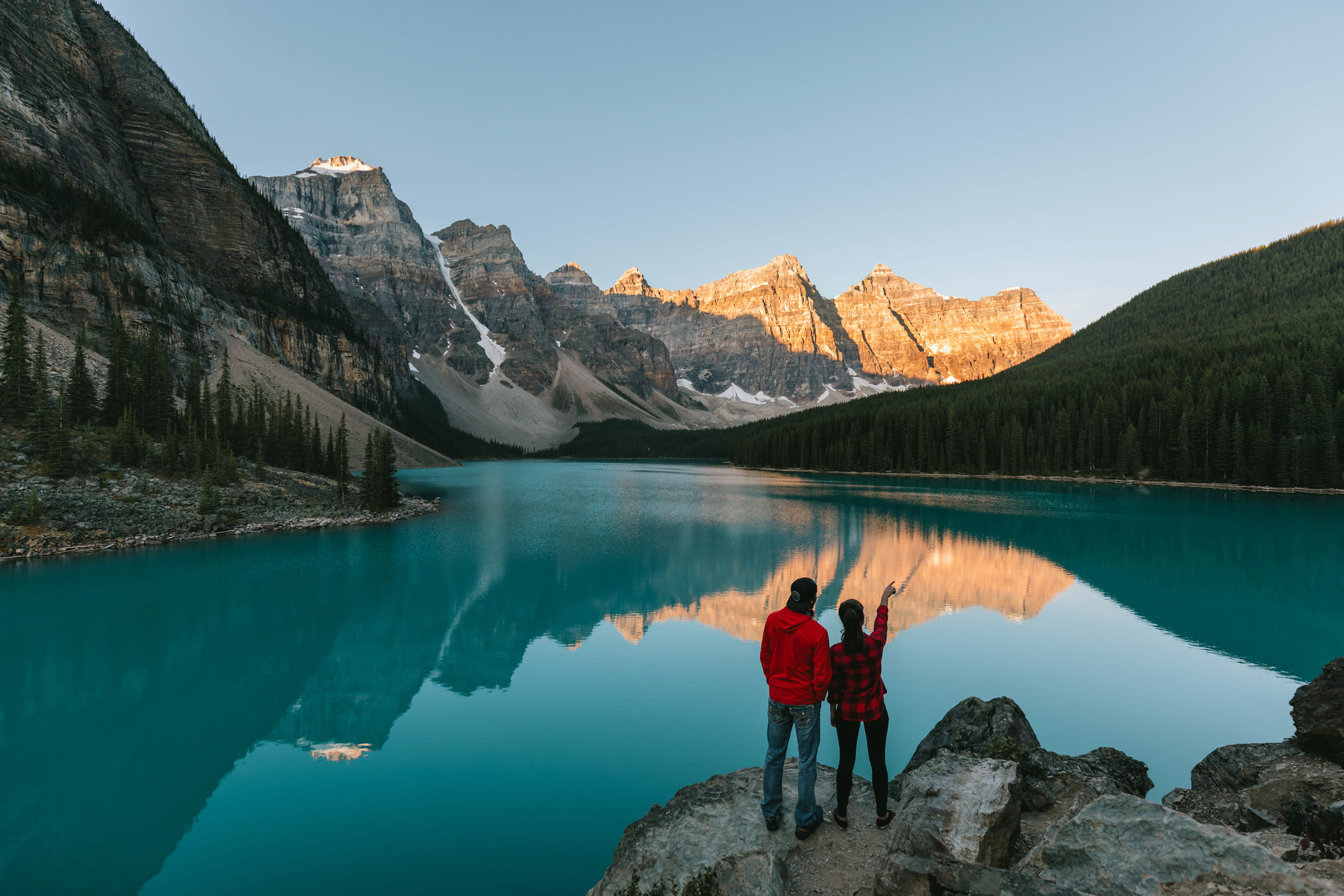 A couple standing by Lake Louise pointing at the surrounding mountains