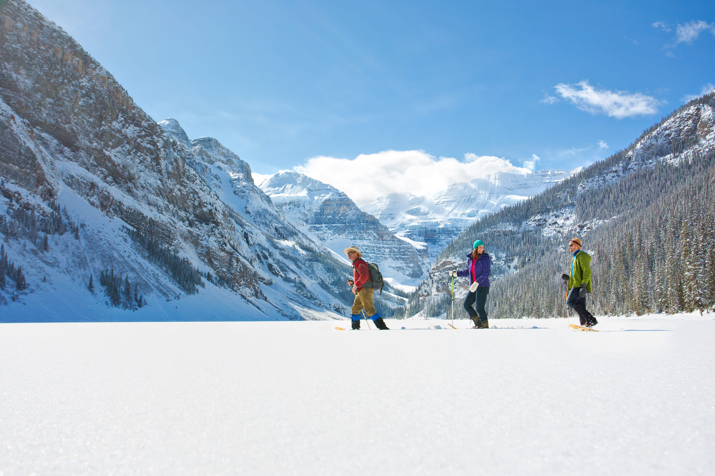 a group of people walking on lake louise in snowshoes