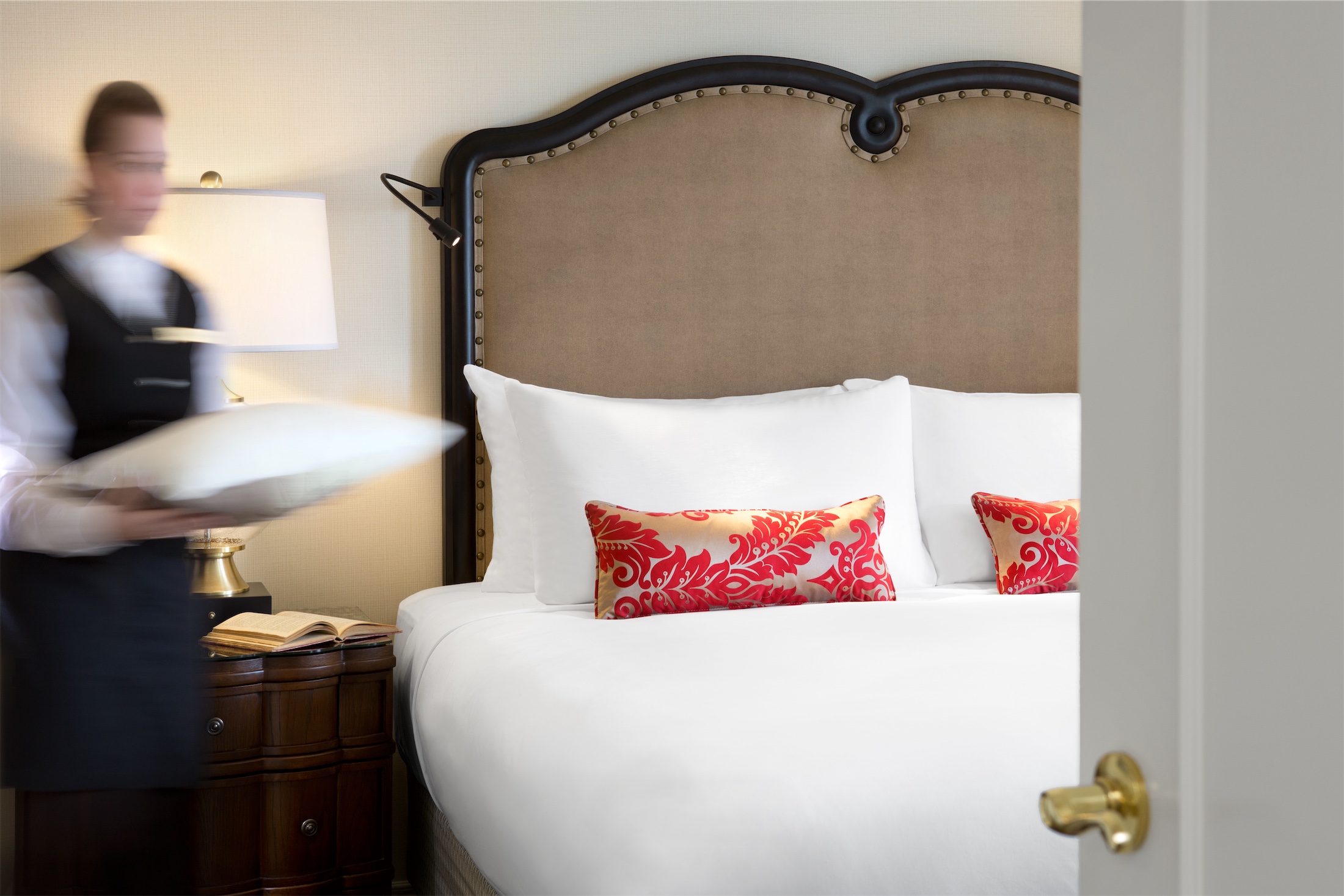 a housekeeper bringing a pillow to the bed