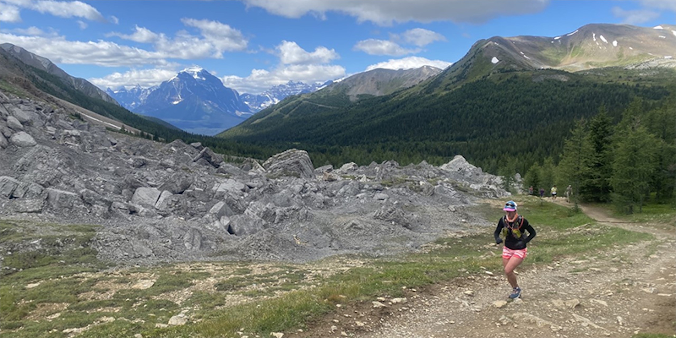 people running on a rocky incline with mountains in the background