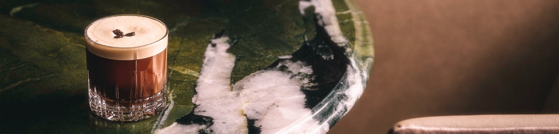 a brown cocktail sits on a marble table