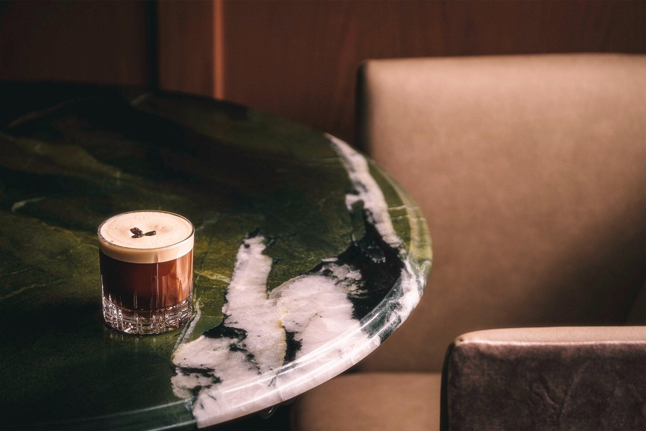 a brown cocktail sits on a marble table