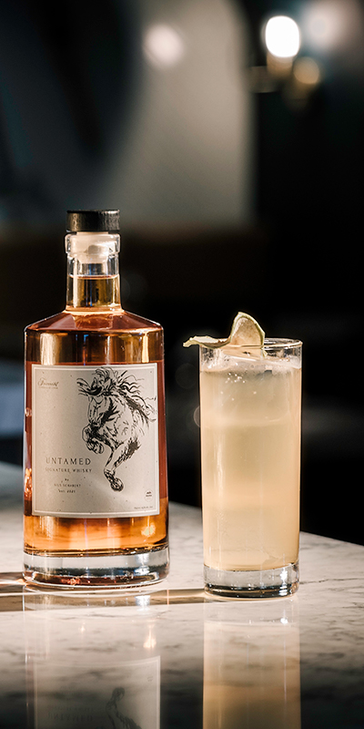 bottle full of whiskey beside a cocktail