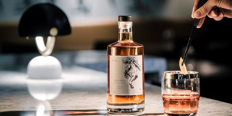 bottle of whiskey beside a cocktail