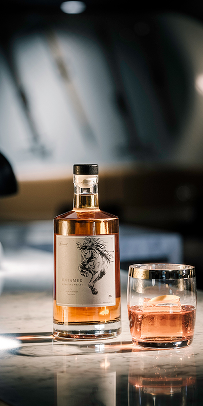 bottle of whiskey beside a cocktail