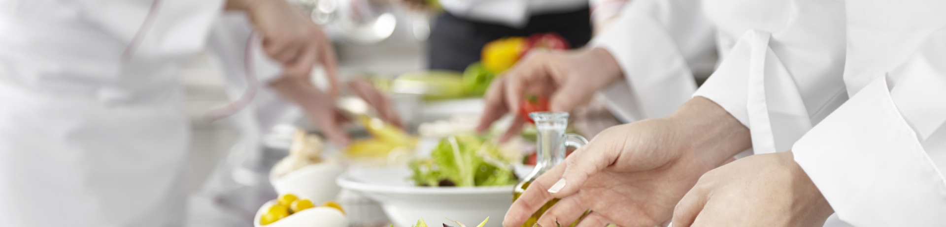 A line of chefs preparing salads in a kitchen