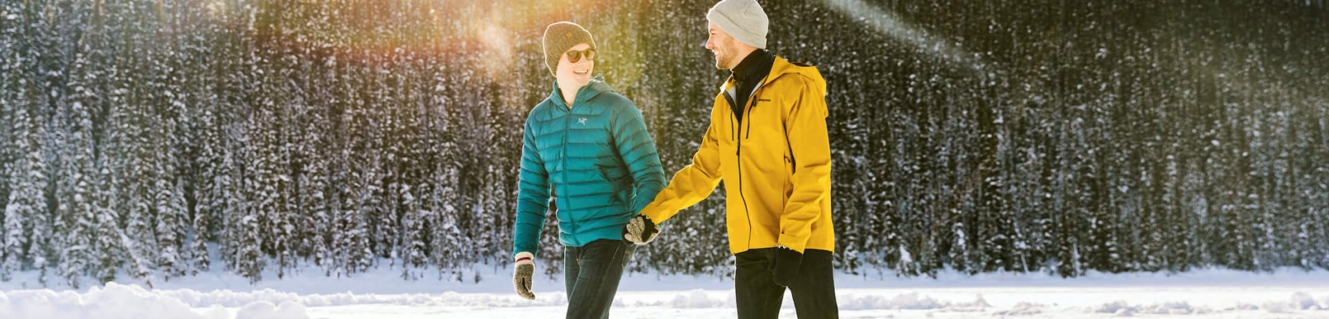 two people in green and yellow jackets skate on icy lake