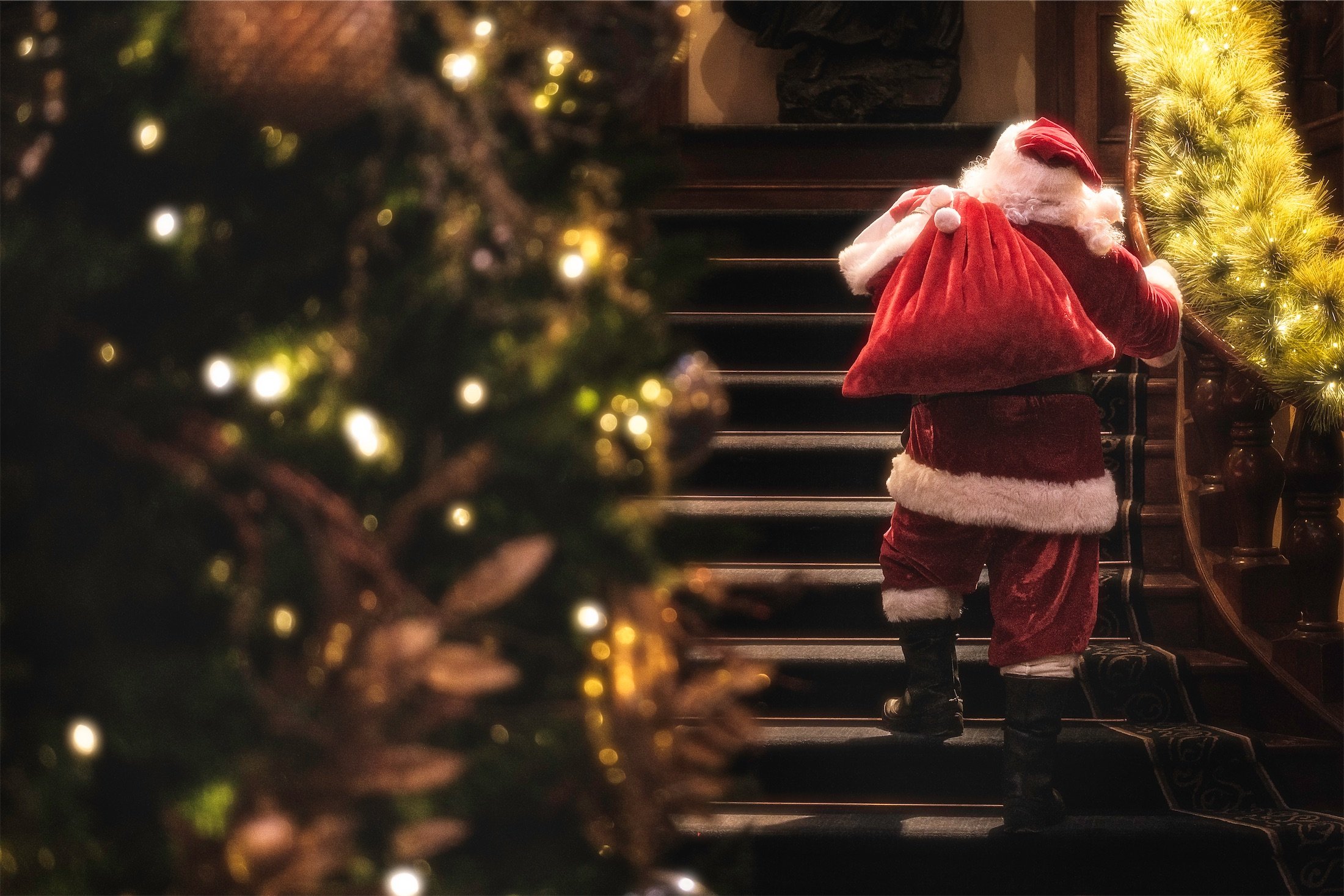 santa holding red bag walks up stairs