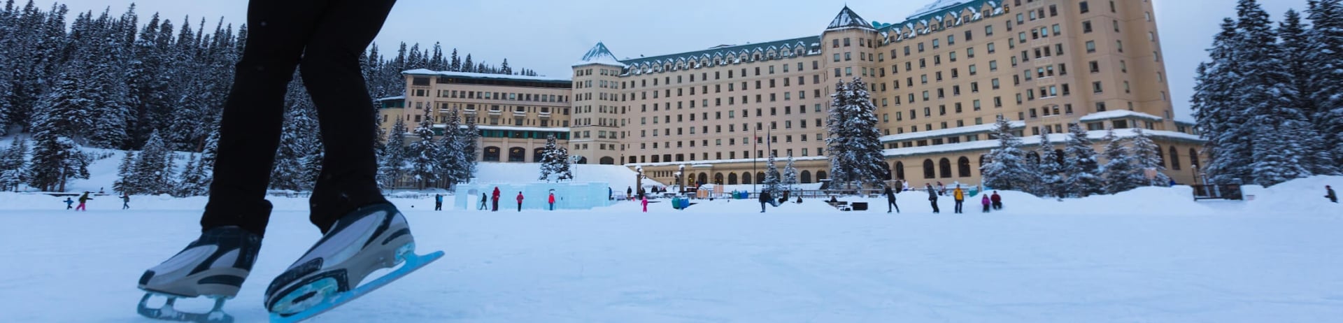 person in red jacket skating in front of Lake Louise lodge