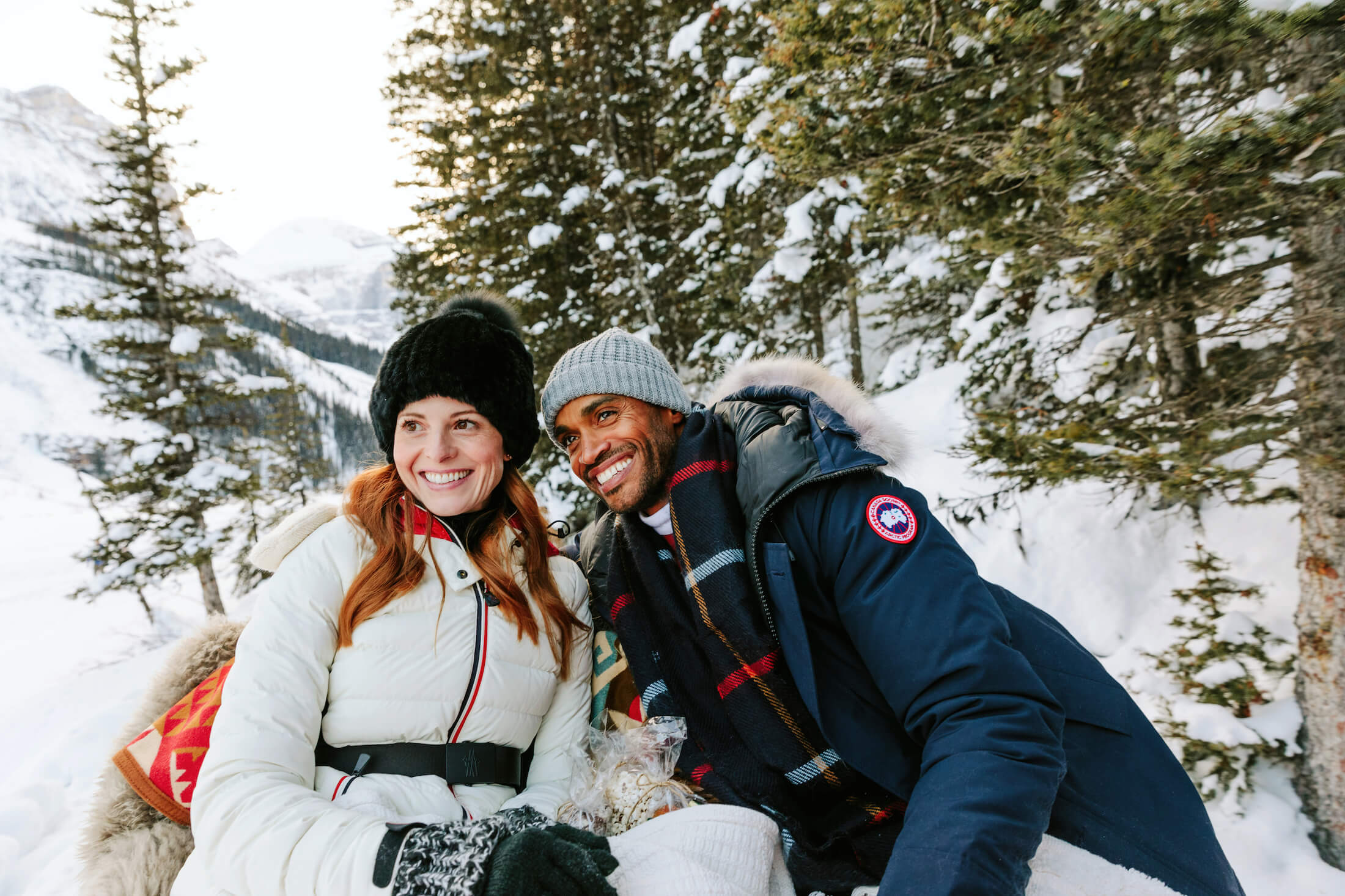 people in winter outfits sit in snowy wooded area