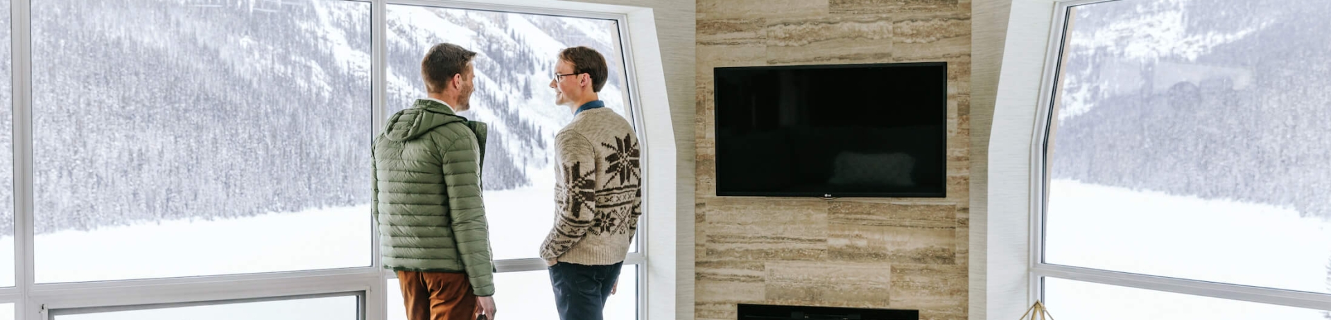 two people stand in front of a window of a hotel room with fireplace 