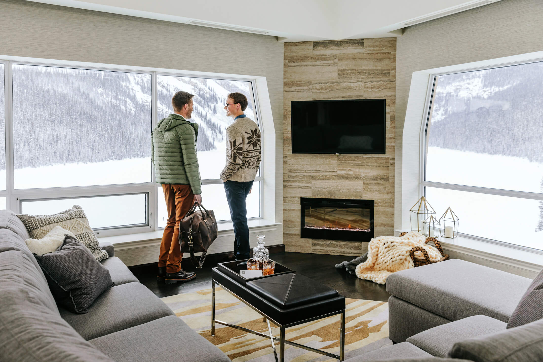 two people stand in front of a window of a hotel room with fireplace 