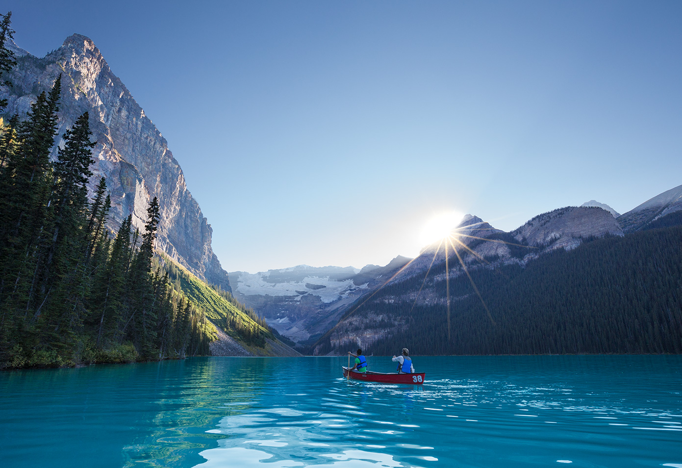 A couple canoeing on a lake surrounded by mountains