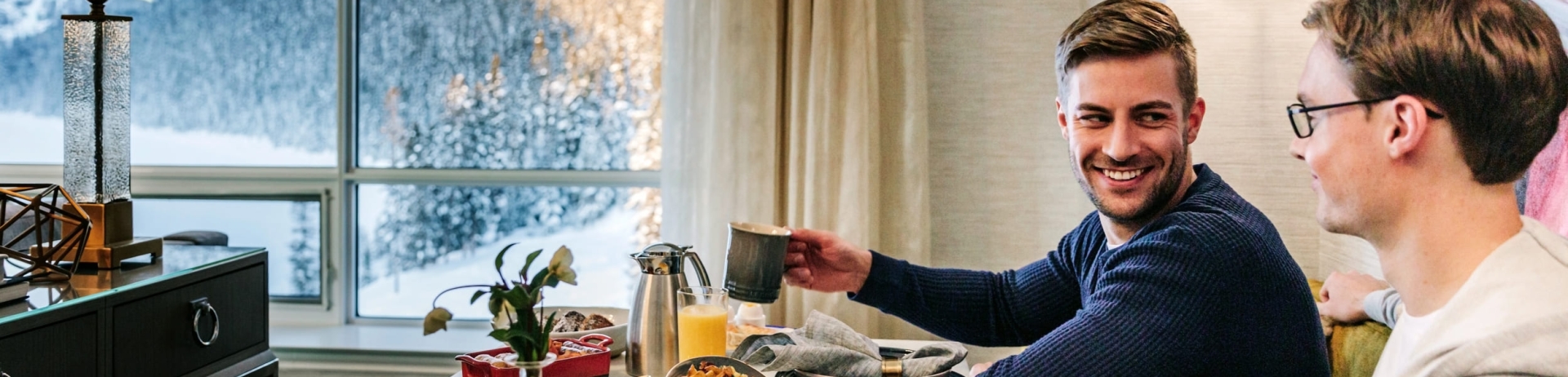 A couple eating breakfast in their hotel room with mountain views