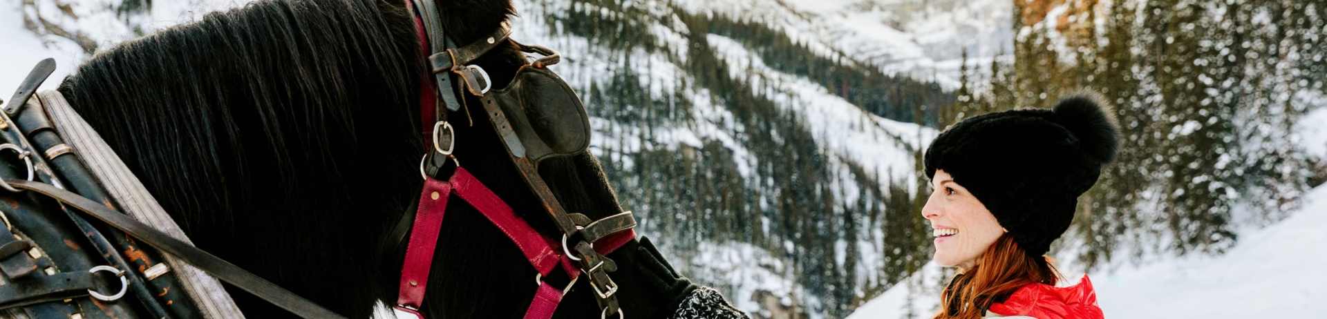 A woman petting a horse outdoors in the winter