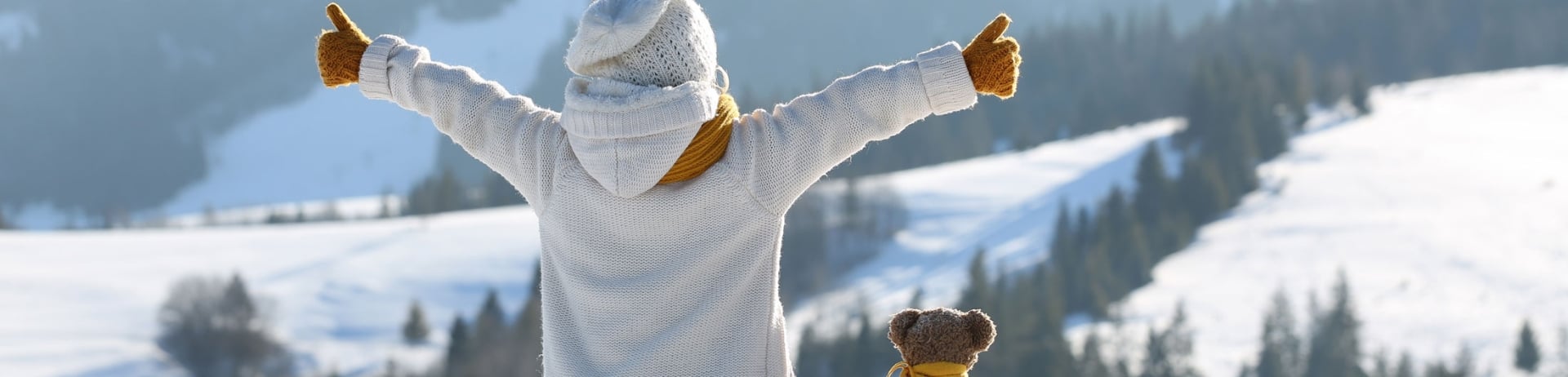 Trees of hope campaign. Child sits on a sled with teddy bear overlooking the snowy landscape.