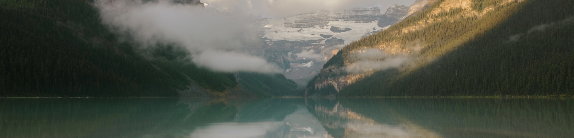 view of lake with low clouds looming over the mountains
