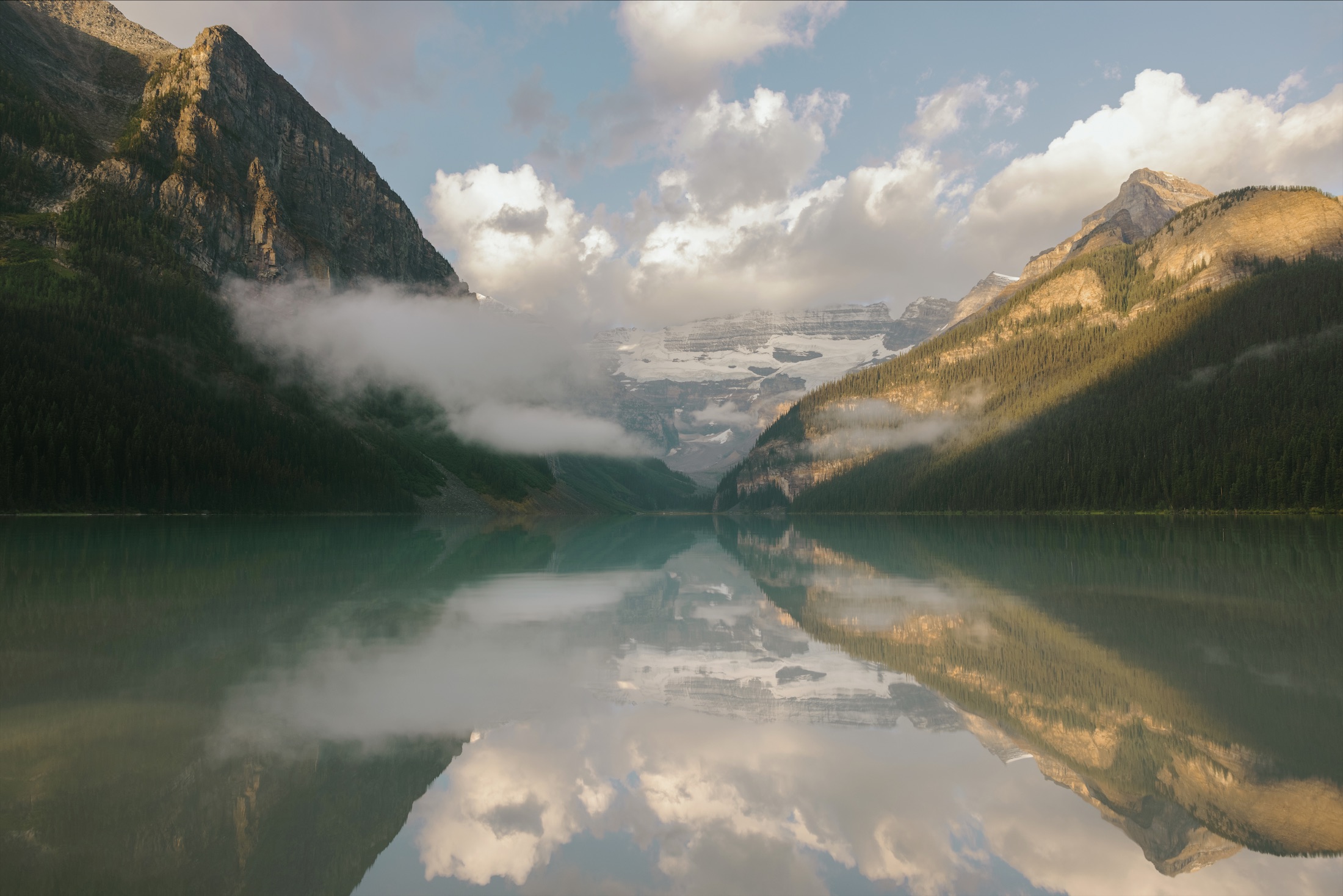 view of lake with low clouds looming over the mountains