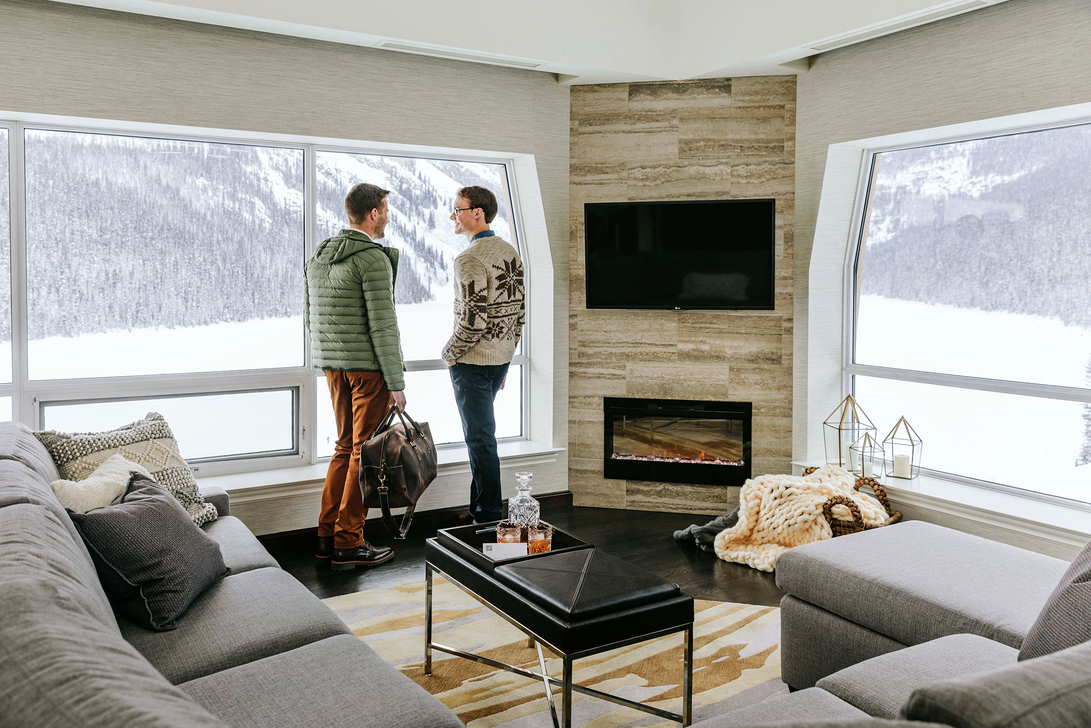 two men looking out the room window with a view of lake louise