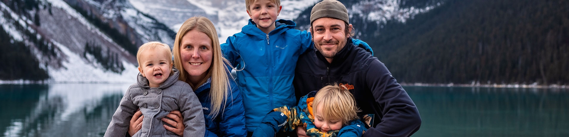 family of five crouched down in front of lake Louise