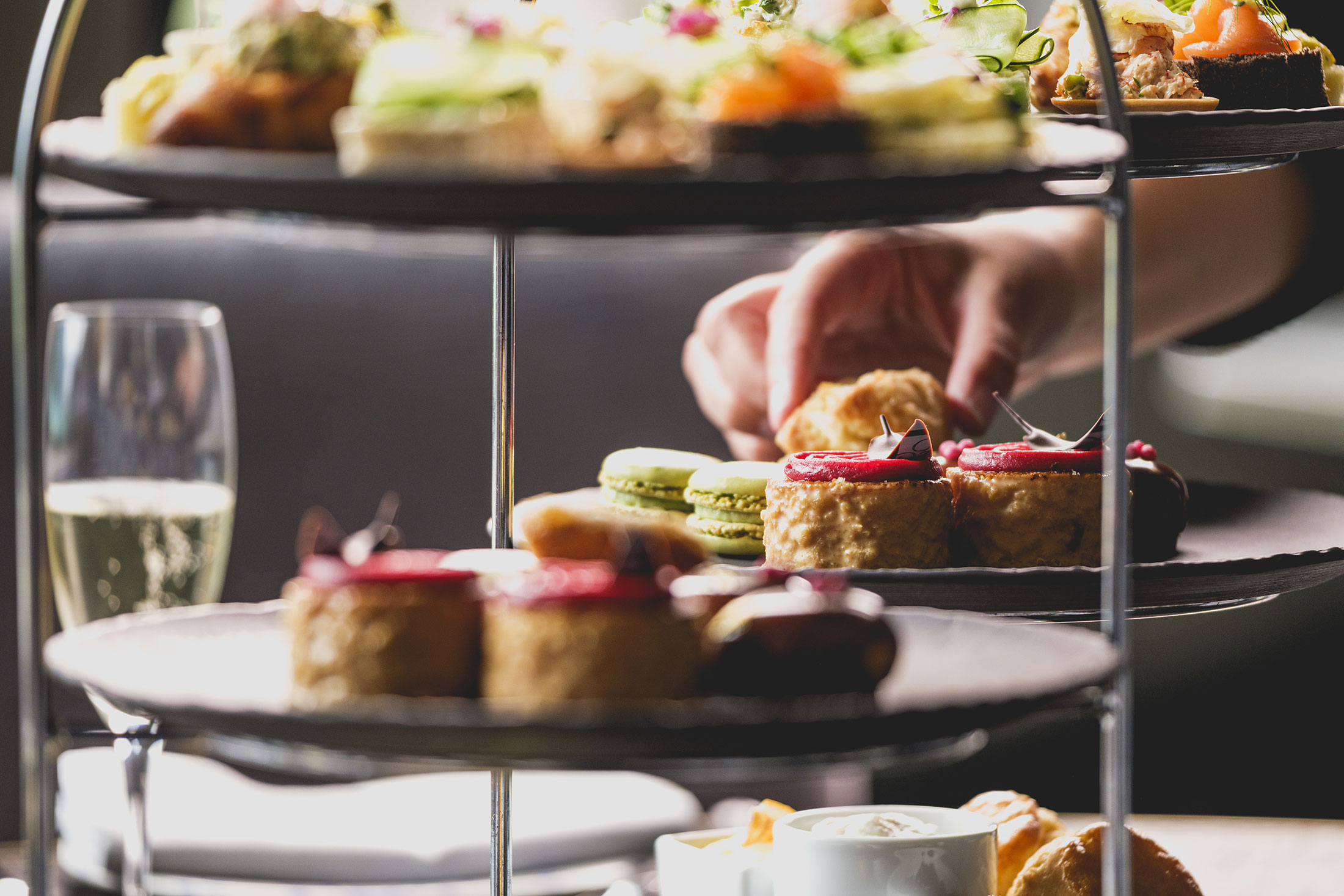 afternoon tea tower with a hand grabbing a cake