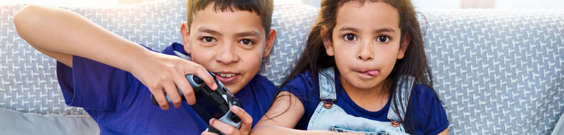 Boy and girl sit on a couch playing video games