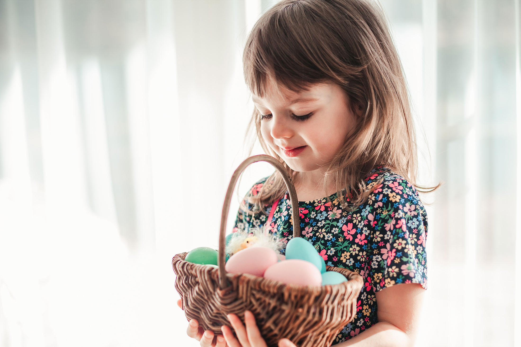 little girl holding a basket full of plastic Easter eggs