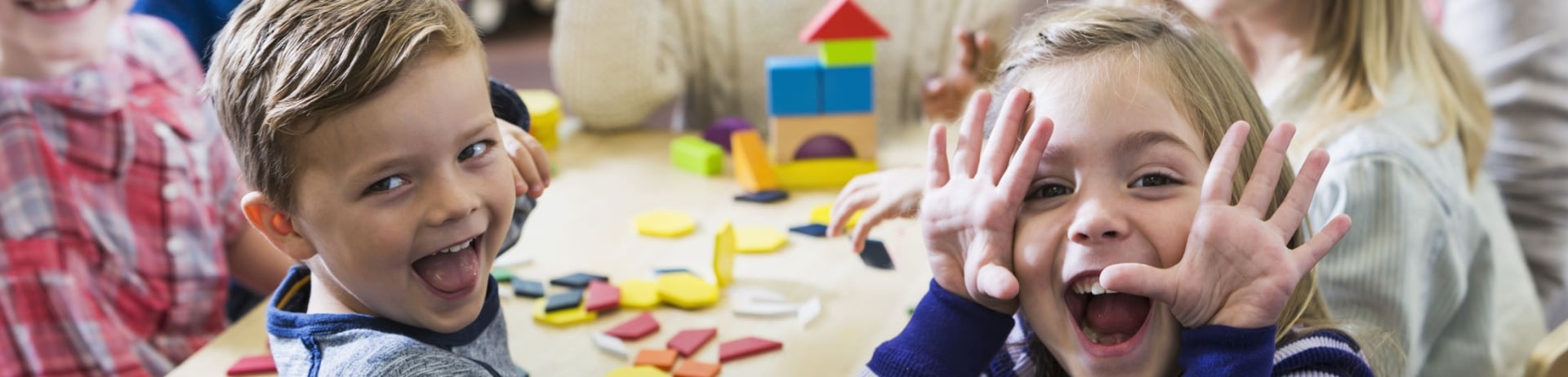 Children having fun around a table with wooden blocks