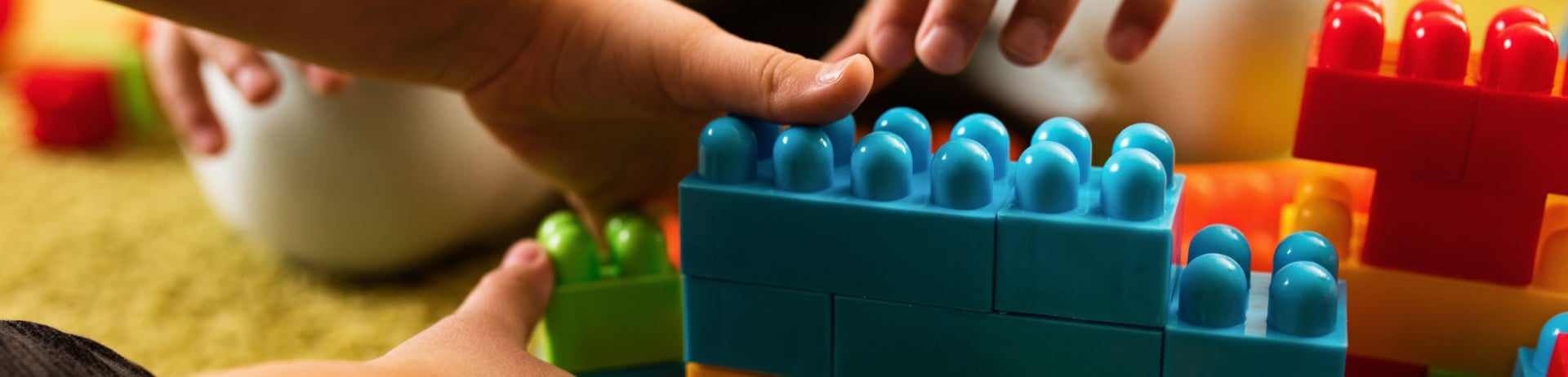 Children's hands close up playing with large colourful building blocks
