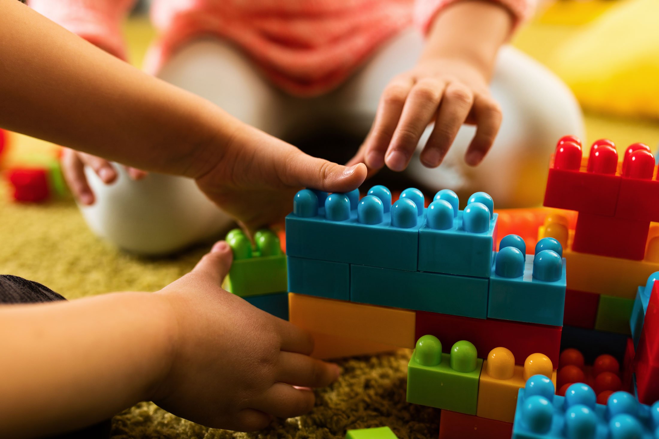 Children's hands close up playing with large colourful building blocks