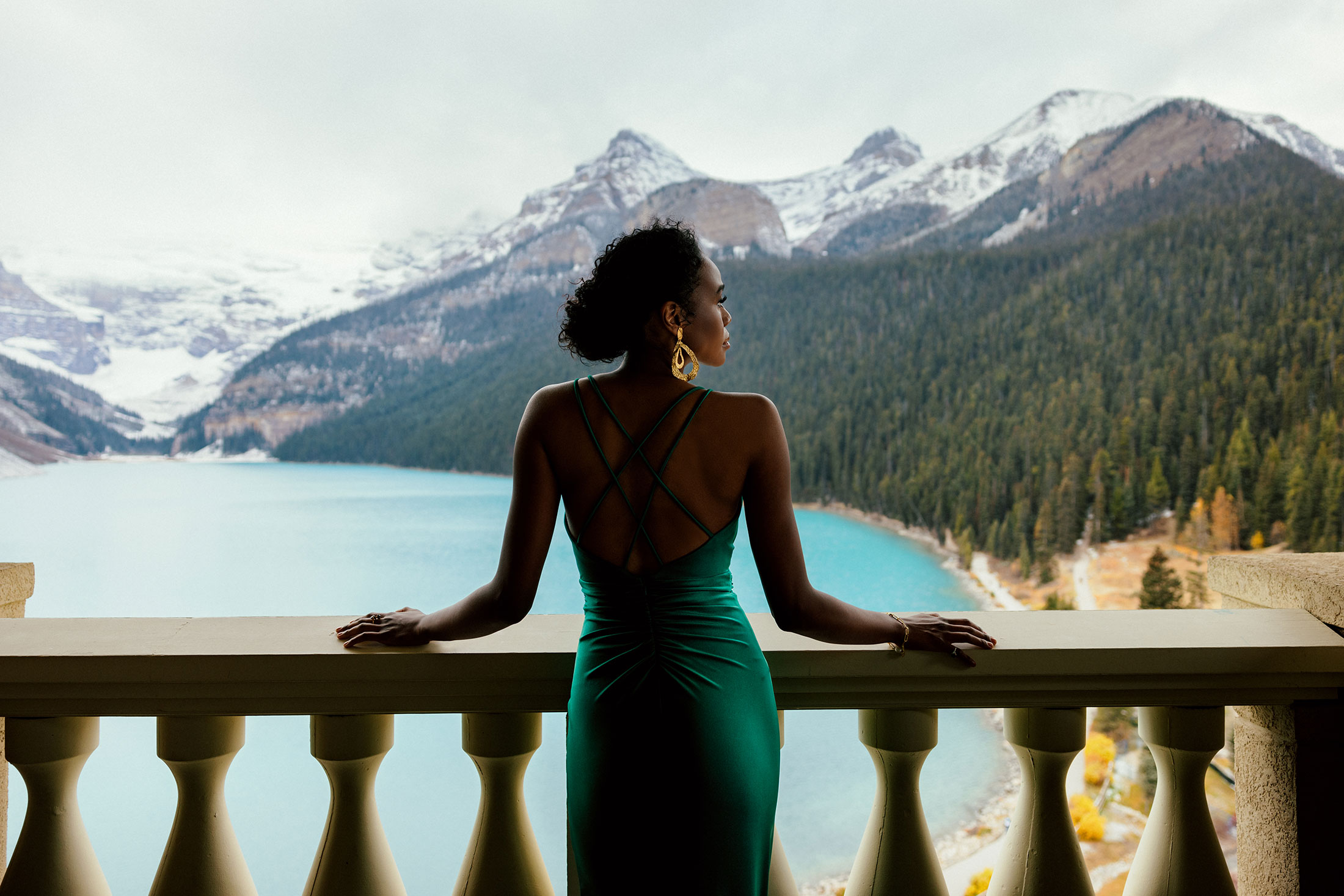 girl stands on hotel balcony overlooking Lake Louise