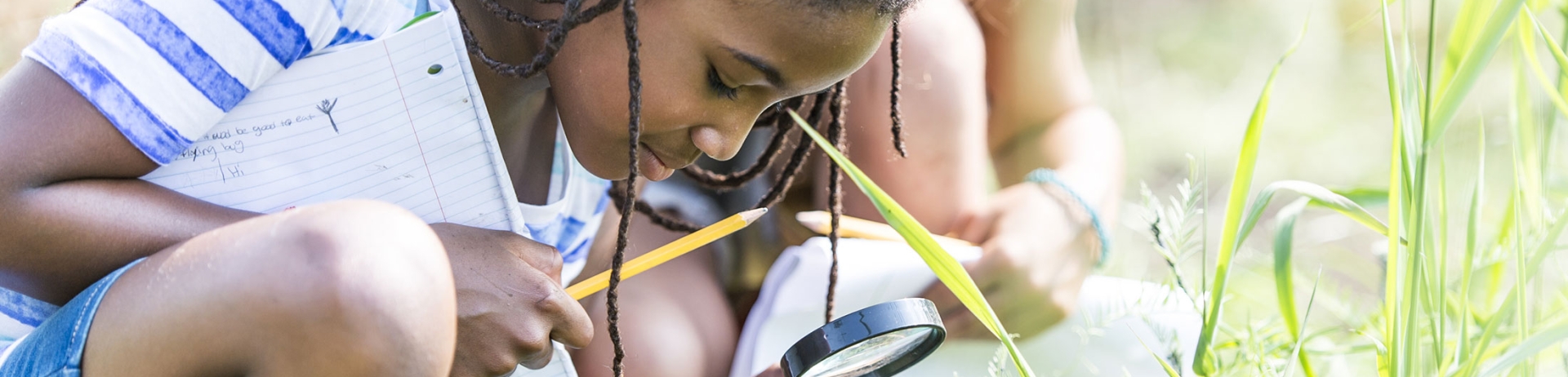 CHild looking through a magnifying glass at the ground