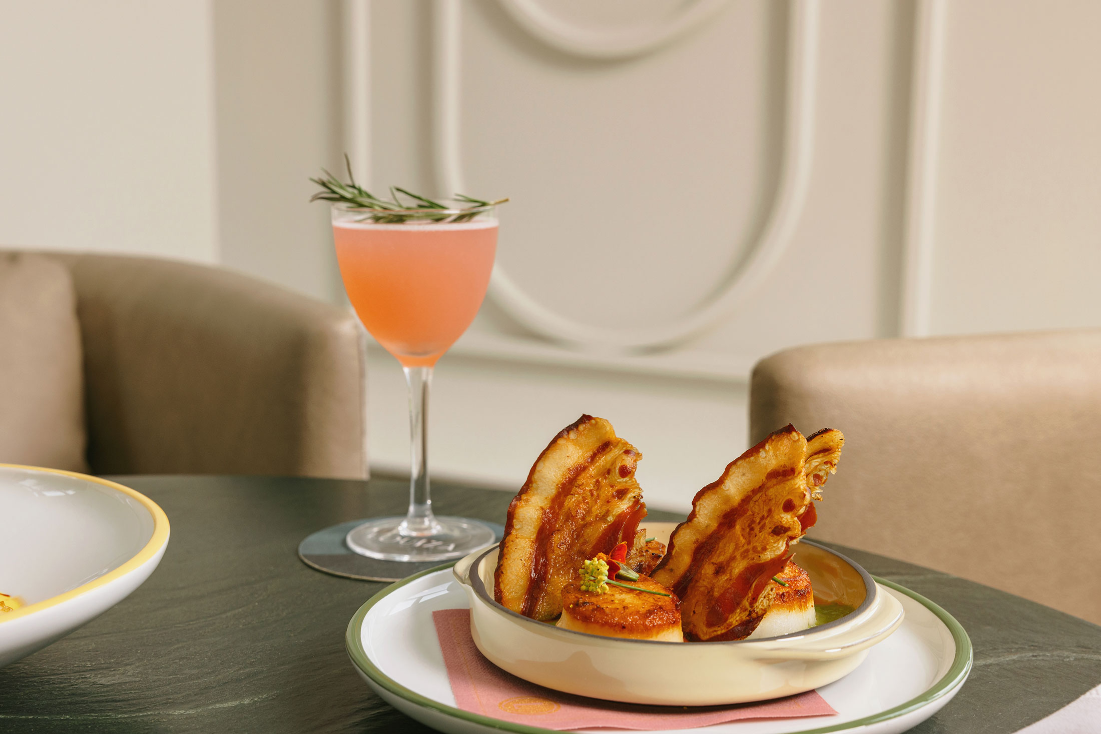 Rhubarb Gimlet cocktail with a rosemary sprig accompanied by seared scallops