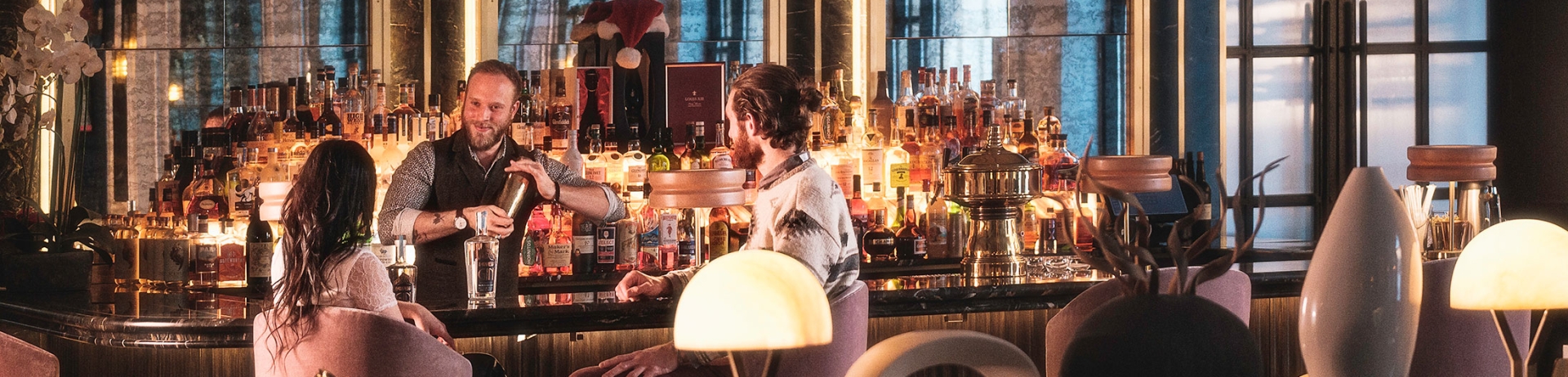 Couple at the bar with a bar tender shaking a bosten cocktail shaker