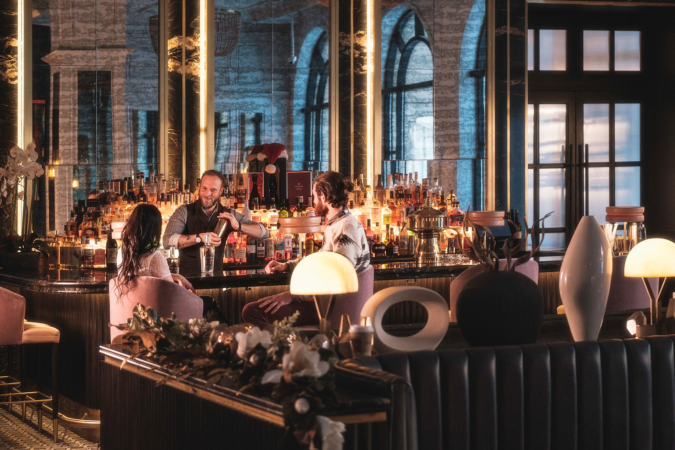 Couple at the bar with a bar tender shaking a bosten cocktail shaker