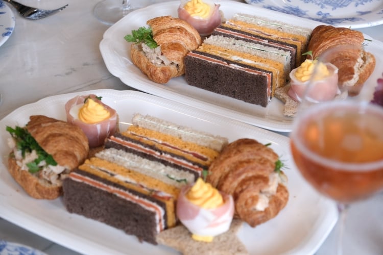 Dainty finger sandwiches on plate with champagne