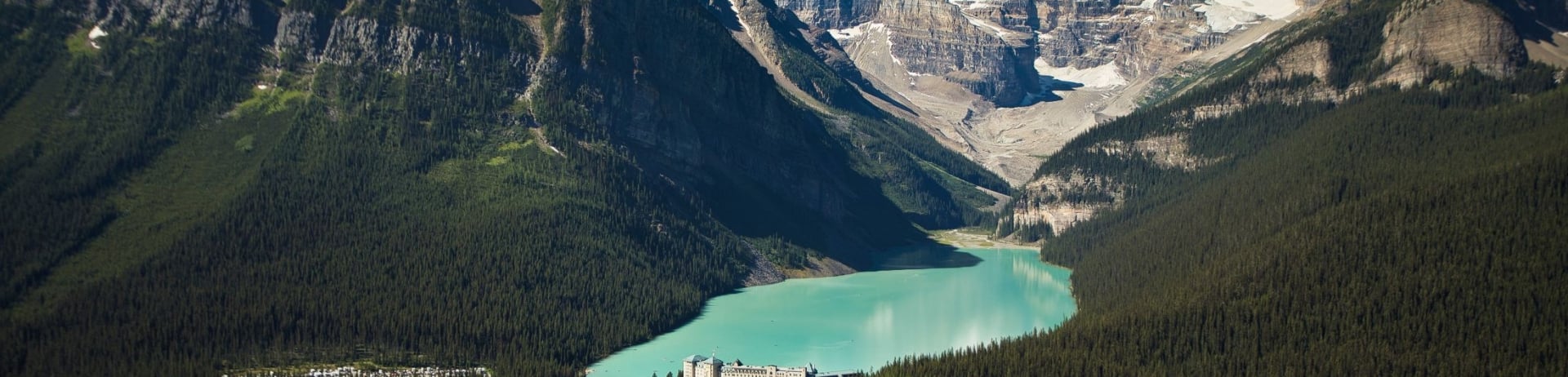 A distant shot of Fairmont Chateau Lake Louise surrounded by mountains