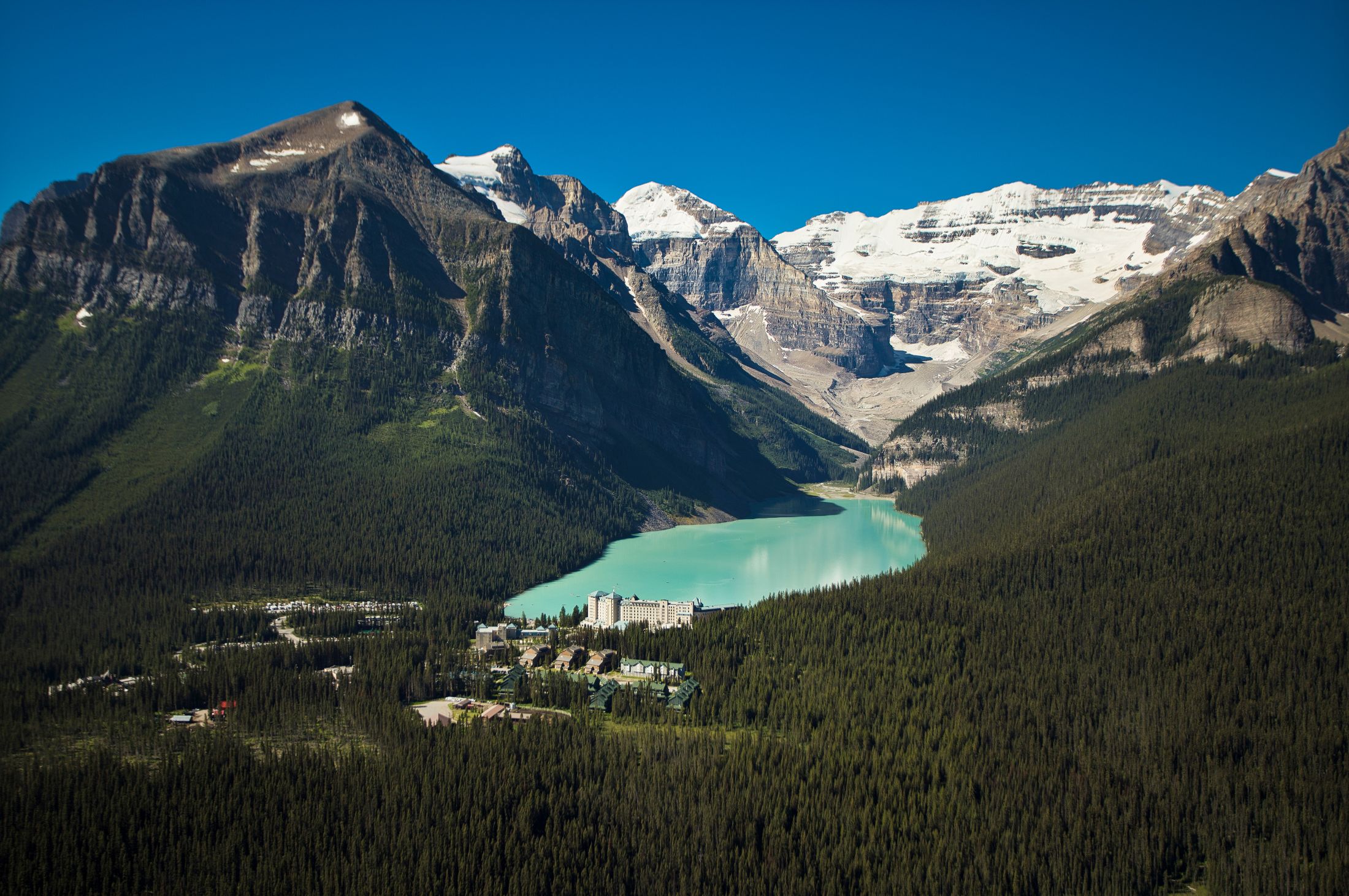 A distant shot of Fairmont Chateau Lake Louise surrounded by mountains